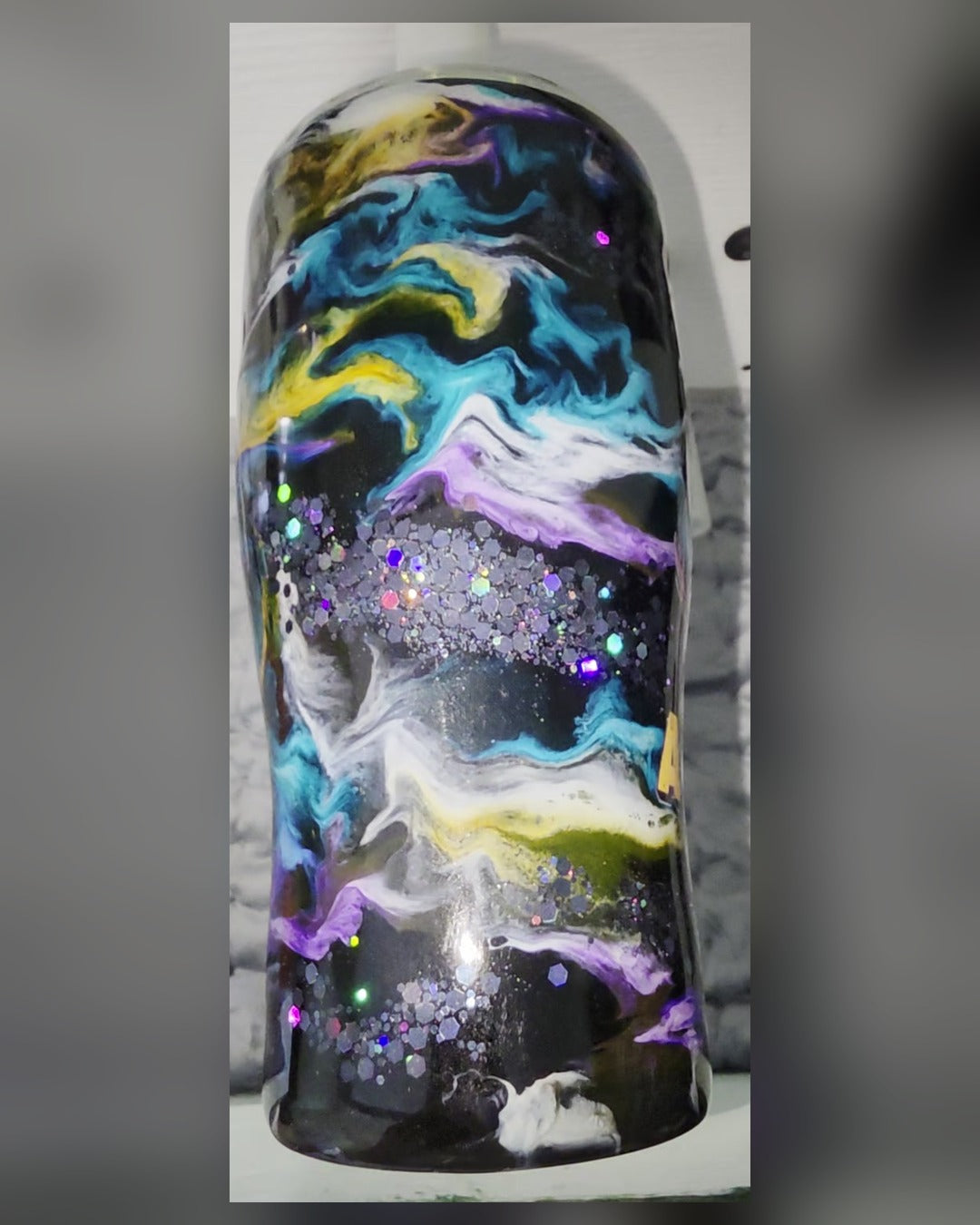 Back of duck tumbler showing black, blue, purple and gold epoxy swirls with chunky holographic glitter band